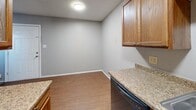 Located at 2704 NW 52nd St in Lawton, Oklahoma, this single-floor, one-bedroom, one-bathroom unit offers a practical and well-organized layout. The kitchen is efficiently designed with warm wood cabinetry, granite-look countertops, a built-in dishwasher, a white range, and a full-size refrigerator. Light-toned vinyl plank flooring runs throughout the kitchen and living areas, complemented by a textured ceiling and flush-mount lighting. The bedroom offers a comfortable, carpeted retreat with a ceiling fan, a window that brings in natural light, and access to two closets, providing generous storage for the space. The bathroom is cleanly appointed with a single-sink vanity featuring a wood cabinet base, a toilet, and a tub-shower combination with a curtain rod. Neutral gray walls throughout the unit create a calm, cohesive atmosphere. The open layout makes efficient use of the available square footage, with a clear flow between the kitchen, living area, and bedroom. Overall, the unit presents a straightforward and functional living environment suited for individuals or couples seeking a manageable, low-maintenance space in Lawton.