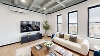 Located at 28 N Saginaw St in Pontiac, MI, this thoughtfully designed one-bedroom, one-bathroom unit offers a compelling blend of industrial character and modern refinement across a single floor. A welcoming hallway with light hardwood flooring and an arched black-framed glass door sets the tone for the space's design aesthetic.

The open-concept living, dining, and kitchen area is a standout, featuring exposed coffered ceilings with visible structural beams that lend an industrial loft feel. Large black-framed windows flood the space with natural light and offer urban views of the surrounding cityscape. The kitchen is well-appointed with taupe wood cabinetry, white quartz countertops, a waterfall island with breakfast bar seating, stainless steel appliances, and a subway tile backsplash.

The living area provides generous room for comfortable furnishings and benefits from the same dramatic ceiling detail. The bedroom is a serene retreat with recessed lighting, dual black-framed windows, clean white walls, and a sliding barn-style closet door. The bathroom features marble-look tile flooring, a sleek walk-in glass shower with black fixtures, and a clean white vanity. In-unit laundry adds everyday convenience to this well-configured urban residence.