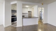 Located on the 9th floor at 3122 Hurontario St in Mississauga, this well-appointed 3-bedroom, 2-bathroom unit offers a thoughtfully designed layout across a generous floor area. The entrance leads into a hallway that connects all areas of the home seamlessly.

The kitchen is a standout feature, equipped with stainless steel appliances including a refrigerator, electric range, and over-the-range microwave. White cabinetry, a herringbone tile backsplash, dark countertops, and light tile flooring give the kitchen a clean, modern aesthetic. A peninsula provides additional prep space and separation from the living areas.

The combined dining and living room is an open, versatile space with classic parquet hardwood flooring that extends throughout the bedrooms and hallway. Three well-sized bedrooms offer natural light through windows, with the primary bedroom featuring mirrored sliding closet doors. All bedrooms benefit from baseboard heating.

Both bathrooms are finished with neutral tile flooring and dark-toned vanities. The main bathroom includes a full tub-shower combo with classic white subway tile surround, while the second bathroom features a vanity with a large mirror.

Completing the unit is a private balcony and five closets, providing ample storage throughout.