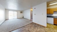 Located at 3322 31st Ave S in Fargo, ND, this single-floor unit offers three bedrooms, two bathrooms, and a practical layout designed for comfortable everyday living. The living room is generously sized, featuring plush carpeting, a sliding glass door that brings in natural light, a wall-mounted AC unit, and a textured ceiling. Tile flooring flows through the entryway, which is accented by a classic pendant light fixture and a mirrored closet. The kitchen is well-appointed with warm oak cabinetry, dark countertops, a double sink, a dishwasher, and a full-size refrigerator, all set on durable tile flooring. Each of the three bedrooms is carpeted and equipped with baseboard heating, and several feature wood-trimmed windows that allow natural light in. Closets with sliding or bifold doors provide ample storage in the bedrooms. The bathrooms include a full tub-shower combo and built-in wire shelving for additional storage, with tile flooring throughout. A connecting hallway links the bedrooms and bathrooms, contributing to a cohesive and functional floor plan. The overall aesthetic is clean and neutral, offering a straightforward and move-in-ready living environment.
