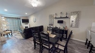 This single-floor residence offers a thoughtfully designed layout that balances functionality with stylish décor throughout. The open-concept living and dining area serves as the heart of the home, featuring wood-look luxury vinyl plank flooring, neutral-toned walls, and elevated ceilings that enhance the sense of space. The dining area accommodates a large black dining table with seating for six, while the adjacent living room includes a fireplace and wall-mounted television. Decorative wall art and metallic accents add a refined touch to the shared space.

The kitchen is generously proportioned, equipped with warm-toned wood cabinetry, marble-style countertops, and a full suite of stainless steel appliances including a gas range, microwave, dishwasher, and refrigerator. A crystal chandelier serves as a striking focal point overhead. A walk-in pantry provides substantial additional storage.

The bedrooms feature plush carpeting and textured ceilings. The primary bedroom includes a window with natural light, an electric fireplace, and dark wood furnishings. A secondary bedroom offers a large sliding closet and flexible use as a sitting room. The bathroom features a marble-style vanity and wood-look flooring. A dedicated utility room houses the water heater, furnace, and laundry appliances.