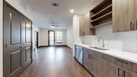 Located at 1400 Henderson St in Fort Worth, TX, this well-appointed one-bedroom, one-bathroom residence offers a thoughtfully designed single-level layout. Rich wood-look flooring flows throughout the main living areas, complemented by neutral walls and dark baseboards that create a clean, contemporary aesthetic. The open-concept kitchen is outfitted with warm wood cabinetry, a textured tile backsplash, light quartz countertops, a stainless steel sink, and a full suite of stainless steel appliances including a side-by-side refrigerator with ice maker, electric range, microwave, and dishwasher. The living room connects seamlessly to the kitchen and receives natural light through large windows and a glass door leading to the private patio, with a ceiling fan adding comfort overhead. The generously sized bedroom features plush carpeting, a wide window with exterior views, and access to a dedicated closet with built-in shelving and hanging rods. The bathroom offers a wood-toned vanity with a white countertop, a large mirror, and additional wall-mounted cabinetry. A separate utility and laundry area adds everyday convenience. This residence combines modern finishes with a functional floor plan in a prime Fort Worth location.