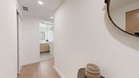 Located on the 14th floor of a high-rise along Wilshire Boulevard in Los Angeles, this thoughtfully designed 2-bedroom, 2-bathroom residence offers a clean, modern aesthetic throughout. Light wood flooring flows seamlessly across the open-plan living, dining, and kitchen areas, anchored by dramatic floor-to-ceiling windows that frame sweeping panoramic views of the Los Angeles skyline and the San Gabriel Mountains beyond. The dining area takes full advantage of these views, creating an airy, light-filled space ideal for entertaining. The kitchen is outfitted with stainless steel appliances, white flat-front cabinetry extending to the ceiling, and a clean white countertop, all contributing to a streamlined, contemporary look. The primary bedroom is generously proportioned with large windows capturing city views, and is complemented by a walk-in closet with built-in shelving and hanging rails. Its en-suite bathroom features a soaking tub, glass-enclosed shower, marble-style tile flooring, and a warm wood vanity with an illuminated mirror. The second bedroom offers ample closet space and a calm, neutral palette. The second bathroom includes a glass-enclosed walk-in shower, matching tile flooring, and a backlit vanity mirror. A welcoming hallway with recessed lighting and warm wood flooring connects all spaces cohesively.