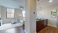 Located within the iconic Terminal Tower in downtown Cleveland, Ohio, this one-bedroom, one-bathroom residence offers a well-appointed single-floor layout with a refined urban aesthetic. The open-concept living and kitchen area is anchored by rich hardwood flooring that flows seamlessly throughout, complemented by neutral-toned walls and a ceiling fan overhead. Large windows frame views of the surrounding cityscape, filling the space with natural light.

The kitchen is outfitted with warm cherry wood cabinetry, dark granite countertops, a subway tile backsplash, and stainless steel appliances including a built-in microwave, range, and refrigerator. A peninsula with bar seating and pendant lighting creates a functional and stylish dining area. An in-unit stacked washer and dryer is conveniently accessible from the main living space.

The bedroom features plush carpet, a ceiling fan, and a window with a city-facing outlook. It includes a dedicated walk-in closet with built-in shelving and hanging rods. The bathroom is finished with large-format tile flooring, a spacious frameless glass-enclosed shower with floor-to-ceiling tile surround, and clean, contemporary fixtures. This residence combines modern finishes with a prime downtown location in one of Cleveland's most recognized landmarks.