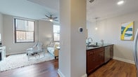 Located within the iconic Terminal Tower in downtown Cleveland, Ohio, this one-bedroom, one-bathroom residence offers a well-appointed single-floor layout with a refined urban aesthetic. The open-concept living and kitchen area is anchored by rich hardwood flooring that flows seamlessly throughout, complemented by neutral-toned walls and a ceiling fan overhead. Large windows frame views of the surrounding cityscape, filling the space with natural light.

The kitchen is outfitted with warm cherry wood cabinetry, dark granite countertops, a subway tile backsplash, and stainless steel appliances including a built-in microwave, range, and refrigerator. A peninsula with bar seating and pendant lighting creates a functional and stylish dining area. An in-unit stacked washer and dryer is conveniently accessible from the main living space.

The bedroom features plush carpet, a ceiling fan, and a window with a city-facing outlook. It includes a dedicated walk-in closet with built-in shelving and hanging rods. The bathroom is finished with large-format tile flooring, a spacious frameless glass-enclosed shower with floor-to-ceiling tile surround, and clean, contemporary fixtures. This residence combines modern finishes with a prime downtown location in one of Cleveland's most recognized landmarks.