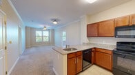 Located at 2701 Neabsco Common Pl in Woodbridge, VA, this two-bedroom, one-bathroom unit offers a well-organized single-floor layout with a thoughtful use of space throughout. The kitchen is a standout feature, equipped with warm cherry wood cabinetry, granite countertops, black appliances including a range, microwave, dishwasher, and refrigerator, and light tile flooring. A peninsula with a built-in sink and additional granite counter space opens toward the living area, creating a connected, functional flow. The living area is finished with plush wall-to-wall carpeting that continues throughout the bedrooms, lending a comfortable, cohesive feel. Each bedroom benefits from natural light through large windows with views of mature trees, and ceiling fans provide added comfort. The primary bedroom features crown molding and dual windows for additional brightness. The shared bathroom is well-appointed with a granite-topped vanity, rich wood cabinetry, tile flooring, and a full tub-shower combination. A dedicated closet provides convenient storage. Neutral warm-toned walls and clean white trim throughout give the space a bright, move-in-ready appearance.