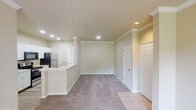 This single-floor residence offers a thoughtfully arranged layout with a warm, neutral color palette throughout. The open-concept living and dining area is anchored by crown molding, recessed lighting, and soft carpeting, with a sliding glass door that invites natural light and outdoor access. A built-in shelving niche adds a distinctive architectural detail to the living space.

The kitchen runs in a galley configuration, featuring white cabinetry, light countertops, wood-look flooring, and stainless steel appliances including a refrigerator, electric range, microwave, and dishwasher. A peninsula with a sink connects the kitchen to the main living area, enhancing functionality.

The bedrooms are carpeted and each equipped with a ceiling fan and light fixture. One bedroom includes a mirrored sliding closet, while another offers direct window views with ample natural light.

Two full bathrooms serve the home. The primary bathroom features a broad vanity with white cabinetry, a large mirror, and a separate tub area. The secondary bathroom includes a tub/shower combo with white tile surround, a single vanity, and wood-look flooring. The entry area transitions from tile flooring into the carpeted living space, creating a practical and welcoming arrival point.