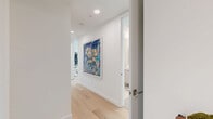 Located on Santa Monica Boulevard in the heart of West Los Angeles, this sophisticated 2-bedroom, 2-bathroom residence offers a thoughtfully designed single-level layout with modern finishes throughout. Light wide-plank wood flooring flows through the main living areas, complementing a bright, neutral palette that creates a clean, contemporary ambiance.

The open-concept kitchen is a standout feature, outfitted with flat-front cabinetry in soft white, a quartz waterfall island with bar seating, stainless steel appliances including a gas range and French door refrigerator, and a tasteful tile backsplash. A dining area positioned beside floor-to-ceiling sliding glass doors captures sweeping city views and opens to a private balcony, filling the space with natural light.

The living room offers a comfortable, gallery-like atmosphere with recessed lighting and ample wall space. A hallway with light wood flooring connects the bedrooms, each carpeted and serene in tone. The primary bedroom enjoys direct balcony access through large sliding glass doors with panoramic views of the Los Angeles skyline. The second bedroom is equally bright and well-proportioned.

Both bathrooms are finished in light stone tile. One features a soaking tub with full-height surround, while the other offers a frameless glass walk-in shower. Each room includes dedicated closet space, completing this polished urban residence.