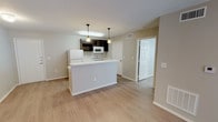 This single-story unit is designed with a practical, open-concept layout that connects the kitchen and living areas into one cohesive space. Light-toned laminate wood flooring runs throughout, creating a clean, uniform aesthetic that ties each room together.

The kitchen is well-equipped, featuring dark espresso-finish cabinetry that contrasts with light countertops and white appliances, including a refrigerator, electric range, and over-the-range microwave. A peninsula with pendant lighting above provides additional prep space and serves as a natural divider between the kitchen and the open living area. A stainless steel sink is integrated into the peninsula for added convenience.

The living area is spacious and airy, benefiting from a sliding glass door that allows natural light to filter in and provides access to an exterior space. A ceiling fan overhead adds functionality and comfort.

The bedrooms are generously sized, each featuring ceiling fans with light fixtures, multiple windows dressed with blinds, and closet storage. One bedroom includes built-in shelving alongside the closet entrance.

The bathroom is thoughtfully designed with a dual-sink vanity featuring dark cabinetry, a large wall mirror with lighted fixtures, and a tub and shower combination with tiled surrounds. The consistent laminate flooring extends into this space, maintaining the unit's cohesive design throughout.
