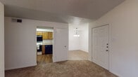 This single-story unit is thoughtfully laid out across a compact, functional floor plan. The living room serves as the central gathering space, distinguished by a vaulted ceiling with a ceiling fan and a tile-surround fireplace that adds a focal point to the room. Plush carpeting runs throughout the living area, contributing to a warm, comfortable ambiance.

Adjacent to the living room, a dedicated dining area is illuminated by a classic chandelier, creating a defined space for meals. The kitchen connects directly to the dining area and features warm wood-toned cabinetry, light-colored countertops, a double-basin sink, and a full suite of appliances including an electric range with overhead ventilation and a dishwasher. Wood-look flooring in the kitchen and dining areas provides easy maintenance and visual contrast to the carpeted zones.

The bedrooms are carpeted and benefit from natural light through blinded windows, offering quiet, private retreats. The bathroom is well-appointed with a wood-toned vanity, light countertop, a decoratively framed mirror, and wood-look flooring. Textured ceilings are consistent throughout, and the overall neutral color palette keeps the space feeling bright and move-in ready.
