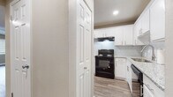 This two-story residence is thoughtfully designed with a clean, neutral aesthetic throughout. The main level features wood-look plank flooring that extends through the living and dining areas, complemented by warm taupe walls and textured ceilings. A ceiling fan with integrated lighting anchors the living space, which receives natural light through a window fitted with horizontal blinds.

The kitchen is well-appointed with crisp white shaker-style cabinetry, granite-look countertops, and a white subway tile backsplash. A black Whirlpool electric range sits beneath a built-in range hood, while additional appliances are housed within the cabinetry. The kitchen connects conveniently to adjacent living spaces via a paneled door.

The bathroom features wood-look flooring, a white vanity with granite countertop, and a tub-shower combination fully tiled in large white subway tile with contrasting dark grout, finished with brushed nickel fixtures.

The bedrooms are carpeted in a neutral tone and include ceiling fans, windows for natural light, and bifold-door closets with hanging rods. The 3D floor plan reveals a staircase connecting the two levels, with living spaces on the lower floor and bedrooms situated above, creating a practical separation of living and sleeping areas.