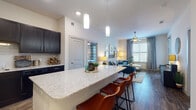 This single-story residence offers a thoughtfully designed open-concept layout that seamlessly connects the kitchen, dining, and living areas. The kitchen is a standout feature, showcasing dark espresso cabinetry, granite countertops, a tile backsplash, and black appliances. A large granite-topped island with pendant lighting above serves as both a functional workspace and a casual dining spot with bar seating.

The living room is bright and welcoming, with wood-style flooring, large windows that invite natural light, and a ceiling fan overhead. A secondary sitting room provides additional flexible living space, also featuring carpet flooring, generous window coverage, and a ceiling fan.

The bedrooms are carpeted and well-lit by large windows with decorative drapery. The primary bathroom features dark navy cabinetry, granite countertops, a framed mirror, wood-style flooring, and a glass-enclosed shower. A second bathroom includes matching dark cabinetry, granite countertops, and a full tub-shower combination. A stacked in-unit washer and dryer is conveniently located nearby. Throughout, the space maintains a cohesive, modern aesthetic with neutral tones and quality finishes.