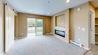 Located at 1130 County Rd in Saint Cloud, MN, this thoughtfully designed one-bedroom, one-bathroom residence offers a comfortable and functional layout across a single floor. The open-concept kitchen and living area serves as the heart of the home, where light wood cabinetry, granite countertops, and a suite of stainless steel appliances create a polished, modern kitchen. A navy blue island with matching granite provides additional prep space and casual seating, while two glass pendant lights add a refined touch overhead. Luxury vinyl plank flooring ties the kitchen seamlessly into the dining and living spaces. The living room is carpeted and anchored by a sleek linear fireplace set within a light wood surround and built-in niche, offering both warmth and visual impact. A sliding glass door opens to a private balcony with outdoor views of lush greenery. The bedroom is carpeted and bathed in neutral tones, with a baseboard heating system and ample natural light from a window. A den provides flexible space for a home office or additional storage. The bathroom features large-format tile flooring, a wood-tone vanity with granite countertop, and a stacked washer and dryer unit for in-unit laundry convenience. A wall-mounted mini-split system provides additional climate control throughout the space.