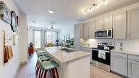 This thoughtfully designed one-bedroom, one-bathroom residence offers an efficient and stylish layout across a single floor. The open-concept kitchen serves as the heart of the home, anchored by a granite-topped island with bar seating — ideal for casual dining or entertaining. The kitchen is outfitted with grey shaker-style cabinetry, white tile backsplash, stainless steel appliances including a refrigerator, range, and built-in microwave, and light wood-style flooring that flows seamlessly throughout the main living areas. The living room is bright and welcoming, featuring a ceiling fan, large windows, and a sliding glass door that invites natural light and provides outdoor access. The bedroom is a comfortable retreat with generous proportions, a ceiling fan, large windows, and direct access to the closet with in-unit stacked washer and dryer. The full bathroom continues the home's cohesive design with granite countertops, grey cabinetry matching the kitchen, wood-style flooring, and a tiled soaking tub and shower combination. Clean white walls, consistent flooring, and modern fixtures throughout lend the space a fresh and cohesive aesthetic.