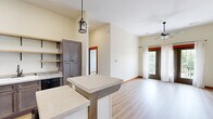 This single-floor, three-bedroom, one-bathroom unit in Bloomington, Indiana offers a well-organized layout across a compact but efficiently utilized footprint. The open-concept living area features light wood-tone vinyl plank flooring, elevated ceilings, and a ceiling fan, with a glass-panel entry door framed in warm wood trim that invites natural light into the space. A dedicated entrance leads directly into the kitchen and living area, creating a seamless flow throughout.

The kitchen is thoughtfully equipped with gray-toned cabinetry, stone-look countertops, black appliances including a range, refrigerator, and dishwasher, and open wood shelving that adds a contemporary, functional touch. A kitchen island with a light stone countertop provides additional workspace and casual seating.

The three bedrooms feature soft carpet flooring, warm wood baseboards, and windows that bring in natural light and outdoor views of the surrounding greenery. The primary bedroom includes a closet with an arched-panel door. The shared full bathroom offers a tub/shower combination with oil-rubbed bronze fixtures and stone-tile flooring.

A utility room housing a stacked washer and dryer adds everyday convenience, while a hallway connects all rooms efficiently throughout the unit.