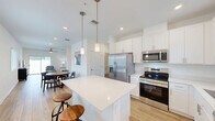 Located at 306 Sugar Mill Dr in New Smyrna Beach, FL, this 2-bedroom, 2-bathroom single-floor unit offers a clean, modern aesthetic throughout. Light wood-look flooring flows seamlessly across every room, creating a bright and cohesive feel.

The open-concept kitchen is a standout feature, showcasing white shaker cabinetry, a large quartz-topped island with bar seating, stainless steel appliances including a French door refrigerator, range, microwave, and dishwasher, and pendant lighting overhead. The adjacent dining area benefits from multiple windows that invite natural light, and connects smoothly to the living room, which is fitted with a ceiling fan and sliding glass doors leading to a private outdoor patio.

The primary bedroom is generously sized and features light-filled windows, wood-look flooring, and ample wall space. The en-suite bathroom includes a walk-in tiled shower with glass sliding doors, a white vanity, and wood-look tile flooring. The second bedroom is well-proportioned with a window offering outdoor views. The second bathroom features a tub-shower combo with glass sliding doors and a matching white vanity. A dedicated closet and hallway utility access complete the layout, making this a well-organized, functional living space.