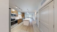 Located at 905 River Rd in Charlottesville, Virginia, this well-appointed one-bedroom, one-bathroom unit offers a thoughtfully designed layout with modern finishes throughout. Light wood-tone flooring flows seamlessly across the entire space, creating a cohesive and contemporary feel.

The open-concept kitchen and living area serves as the heart of the unit. The kitchen is outfitted with rich wood-grain cabinetry, white quartz countertops, a subway tile backsplash, and a full suite of stainless steel appliances including a French door refrigerator, electric range, built-in microwave, and dishwasher. A large central island with pendant lighting provides additional prep space and seating, while track lighting overhead ensures excellent illumination.

The living area is bright and airy, featuring multiple windows with horizontal blinds that invite natural light and outdoor views of the surrounding greenery. A ceiling fan adds comfort, and a private exterior door provides direct outdoor access.

The bedroom is a comfortable and quiet retreat, with a large window framing garden views and its own ceiling fan. The full bathroom features a wood-toned vanity with quartz countertop, a large mirror, and a walk-in shower. An adjacent walk-in closet with built-in shelving offers ample storage, completing this efficiently designed unit.