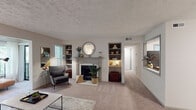 Located at 4601 Baymar Dr in Raleigh, NC, this single-floor residence offers a well-designed layout that balances comfort and functionality throughout. The living room serves as the heart of the home, anchored by a classic fireplace with a detailed white mantel and flanked by built-in bookshelves on either side — an ideal combination of style and storage. Soft carpeting, neutral tones, and abundant natural light from slatted blinds create a warm and inviting atmosphere. An adjoining sunroom or sitting area features sliding glass doors that open onto a private balcony, where treetop views provide a peaceful, nature-filled backdrop. The kitchen is thoughtfully appointed with white shaker cabinetry, stainless steel appliances including a gas range, microwave, and dishwasher, a dark tile backsplash, and light countertops, offering both practicality and modern appeal. The spacious primary bedroom features a large window overlooking lush greenery, plush carpeting, a walk-in closet, and direct access to a private en-suite bathroom. The bathroom includes a full tub and shower combination with clean, bright finishes. Throughout the residence, a cohesive neutral palette and thoughtful architectural details contribute to a comfortable and refined living environment.