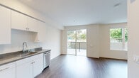 Located at 109 Mission St in Santa Cruz, California, this efficiently designed single-floor unit offers a thoughtfully arranged layout comprising a kitchen, living room, and full bathroom. The open-plan living and kitchen area is anchored by warm hardwood-style flooring that flows seamlessly throughout the space, complemented by crisp white walls and recessed lighting that contribute to a bright, clean aesthetic.

The kitchen is well-appointed with a full suite of stainless steel appliances, including a range, over-the-range microwave, refrigerator, and dishwasher. Ample white cabinetry extends to the ceiling, providing generous storage, while dark granite-style countertops offer a stylish contrast. A stainless steel sink with a modern faucet completes the functional workspace.

The living area benefits from large sliding glass doors that open to a private balcony, flooding the interior with natural light and offering pleasant views of the surrounding neighborhood and greenery. Additional windows throughout the unit further enhance the sense of openness.

The bathroom features a granite-topped vanity with an undermount sink and a large mirror, a full bathtub and shower combination, and consistent hardwood-style flooring. A wall-mounted mini-split system provides climate control. The overall ambiance is modern, clean, and move-in ready, making this a practical and comfortable space in the heart of Santa Cruz.