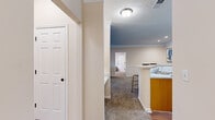 This 2-bedroom, 2-bathroom residence offers a thoughtfully designed single-story layout that maximizes functionality and comfort. The open-concept living, dining, and kitchen area forms the heart of the home. The living room features plush carpeting, crown molding, and a large window that welcomes natural light. The adjacent dining area is accented with chair-rail molding, recessed lighting, and crown molding, lending a refined touch. The kitchen is equipped with warm honey-toned wood cabinetry, black appliances including a refrigerator and range, and a peninsula breakfast bar with seating — ideal for casual dining. Both bedrooms are carpeted and offer a comfortable, private retreat, with the primary bedroom providing a generous footprint. Two full bathrooms each include a tub-shower combination with tile surround and hardwood-style flooring. A dedicated laundry room with wire shelving and hardwood-style flooring adds everyday convenience. Two closets provide ample storage throughout. The consistent use of neutral tones, crown molding, and warm flooring materials creates a cohesive and inviting ambiance throughout the entire residence.