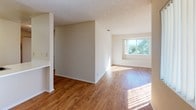 Located at 507–543 W Aviation Rd in Fallbrook, California, this single-floor residential unit offers a well-organized layout with a clean, neutral palette throughout. The open living and dining area is anchored by warm wood-look flooring that extends toward the kitchen, with natural light streaming in through a large sliding window that frames views of the surrounding greenery, creating a bright and welcoming atmosphere.

The kitchen features light wood cabinetry, a white electric range, a refrigerator, and a double-basin sink set into a white countertop with a peninsula-style breakfast bar that opens toward the living space — ideal for casual dining and everyday convenience.

The bedrooms are finished with plush carpeting and neutral walls, providing a soft and comfortable feel. Each room benefits from natural light, with one bedroom offering a generous closet with built-in shelving. Textured ceilings are present throughout the unit.

The bathroom is cleanly appointed with a tub/shower combination, a vanity with sink, and tile flooring, offering a practical and tidy space. Overall, the unit presents a straightforward, move-in-ready living environment in a well-situated Fallbrook location.