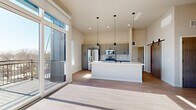 Located at 4607 Monona Dr in Monona, WI, this contemporary 3-bedroom, 2-bathroom residence offers a thoughtfully designed single-floor layout with a bright, open-concept living space. The combined living, dining, and kitchen area is anchored by soaring ceilings and floor-to-ceiling windows that flood the space with natural light and provide sweeping outdoor views. A private balcony extends the living area outdoors. The kitchen is a standout feature, showcasing sleek grey cabinetry, a subway tile backsplash, stainless steel appliances, and a large center island with white quartz countertops and pendant lighting. Light wood-style flooring flows throughout the main living areas, while plush carpeting adds warmth to the bedrooms. The primary bedroom is generously sized, with tall windows framing exterior views. The additional bedrooms offer comfortable proportions and ample closet space. The bathrooms are finished with modern grey vanities, white countertops, and matte black fixtures. A dedicated den, laundry room, and hallway with multiple closets round out this well-appointed and functional home.