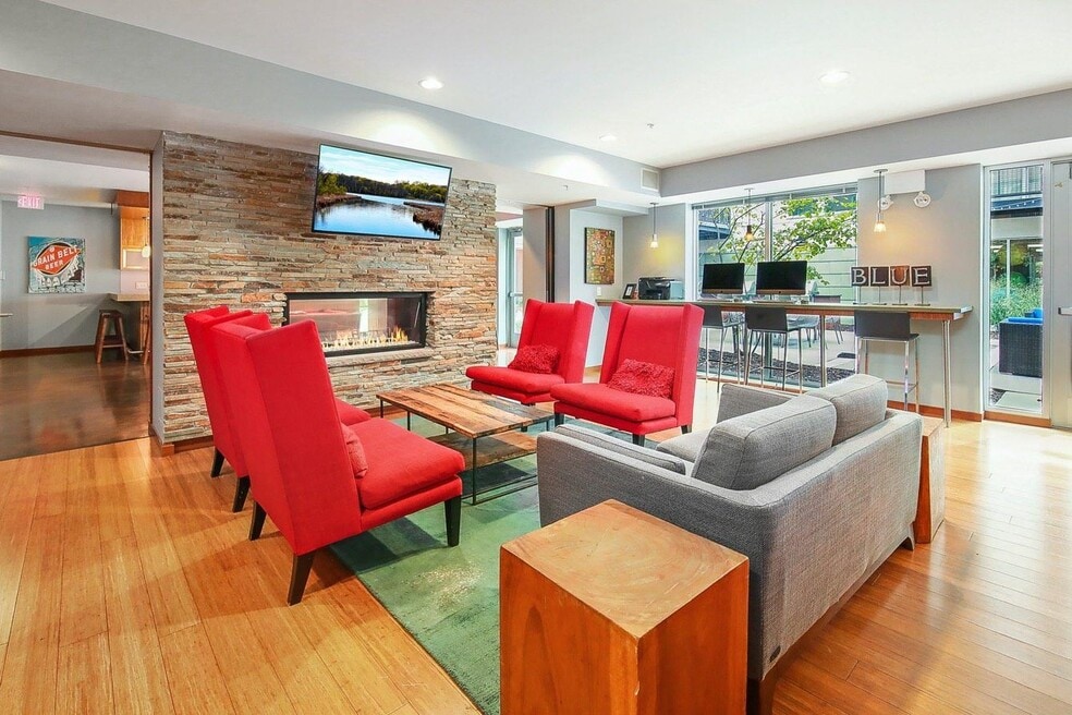 Modern lounge area with fireplace, seating and computer workstations.