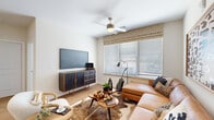 This single-story residence offers a thoughtfully designed layout that balances open communal areas with private retreats. The kitchen serves as a functional centerpiece, featuring white shaker-style cabinetry, granite countertops, a subway tile backsplash, and a full suite of stainless steel appliances including a French door refrigerator, range, microwave, and dishwasher. A central island with an undermount sink and pendant lighting above provides additional prep space and casual seating.

The living area is bright and inviting, with large windows fitted with horizontal blinds and patterned roman shades that allow natural light to fill the room. Light wood-look flooring extends throughout the main living spaces, complemented by a ceiling fan overhead. The bedroom offers a calm, carpeted retreat with generous window exposure and direct access to a spacious walk-in closet outfitted with wire shelving and hanging rods. The bathroom connects via a hallway finished in wood-look flooring, with tile detailing and white cabinetry visible. Overall, the space presents a clean, contemporary aesthetic with warm, cohesive finishes throughout.
