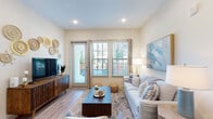 This single-floor residence offers a thoughtfully designed layout with a cohesive, contemporary aesthetic throughout. The living room serves as the heart of the home, featuring wood-style flooring, recessed lighting, and multiple windows alongside a glass door that floods the space with natural light and provides direct outdoor access. Neutral walls and an open feel make this room both welcoming and versatile.

The kitchen is a standout feature, showcasing an elongated granite-topped island with pendant lighting overhead, white shaker cabinetry, open shelving, and a full suite of stainless steel appliances. Wood-style flooring continues here, reinforcing the home's consistent design language.

Each bedroom is carpeted and well-proportioned, offering ample space for full-sized furniture. The primary bedroom benefits from a ceiling fan and multiple windows with outdoor views, while additional bedrooms receive generous natural light from their own windows.

The bathrooms are finished with granite countertops, white cabinetry with brushed nickel hardware, large framed mirrors, and wood-style flooring. Both bathrooms connect directly to walk-in closets with built-in shelving and hanging systems, offering practical storage solutions throughout this refined and comfortable residence.