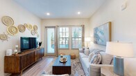 This single-floor residence offers a thoughtfully designed layout with a cohesive, contemporary aesthetic throughout. The living room serves as the heart of the home, featuring wood-style flooring, recessed lighting, and multiple windows alongside a glass door that floods the space with natural light and provides direct outdoor access. Neutral walls and an open feel make this room both welcoming and versatile.

The kitchen is a standout feature, showcasing an elongated granite-topped island with pendant lighting overhead, white shaker cabinetry, open shelving, and a full suite of stainless steel appliances. Wood-style flooring continues here, reinforcing the home's consistent design language.

Each bedroom is carpeted and well-proportioned, offering ample space for full-sized furniture. The primary bedroom benefits from a ceiling fan and multiple windows with outdoor views, while additional bedrooms receive generous natural light from their own windows.

The bathrooms are finished with granite countertops, white cabinetry with brushed nickel hardware, large framed mirrors, and wood-style flooring. Both bathrooms connect directly to walk-in closets with built-in shelving and hanging systems, offering practical storage solutions throughout this refined and comfortable residence.