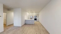 Located at 15922 E Valleyway Ave in Spokane, Washington, this single-floor unit offers a thoughtfully designed interior with a clean, contemporary aesthetic throughout. The open-concept living and kitchen area serves as the heart of the home, where light wood-style flooring and crisp white walls create a bright, airy atmosphere. The kitchen is well-appointed with a suite of stainless steel appliances — including a refrigerator, range, and microwave — complemented by light wood cabinetry, a white quartz countertop peninsula with an integrated sink, and stylish pendant lighting overhead. A dedicated walk-in pantry with wire shelving provides generous storage directly off the kitchen. The living area flows naturally from the kitchen and features access to an exterior door, allowing for natural light to filter in. Bedrooms are finished with plush carpeting and include closets with wire shelving systems. The bathroom features a clean, understated design with a quartz-topped vanity, undermount sink, and a large mirror. Throughout the unit, neutral tones and modern fixtures contribute to a cohesive, move-in-ready environment well-suited for comfortable everyday living.