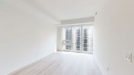 Located on the 19th floor at 3010 Tweedsmuir Ave in Toronto's Forest Hill neighbourhood, this well-appointed one-bedroom, one-bathroom unit offers a clean, modern aesthetic throughout. Light-toned hardwood flooring runs continuously across the space, complementing the crisp white walls and creating a bright, cohesive feel.

The open-concept living and kitchen area forms the heart of the unit. The kitchen is thoughtfully designed with flat-panel white cabinetry, tall built-in storage, a subway tile backsplash, stainless steel appliances including a full-size refrigerator and stove, and a peninsula countertop with an undermount sink — ideal for casual dining or food preparation. Track lighting above the kitchen adds focused illumination to the space.

The living area benefits from expansive floor-to-ceiling windows that flood the room with natural light and frame views of the surrounding Toronto skyline and neighbouring mid-rise buildings.

The bedroom is a well-proportioned, serene retreat featuring large windows with city views and a full-width mirrored sliding closet that enhances the sense of space and reflects natural light throughout the room.

The bathroom is finished with large-format beige floor tiles, full-height wall tiling in the tub surround, and a clean, functional layout with a soaker tub and shower combination.
