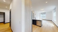 This well-designed one-bedroom, one-bathroom residence at 188 Broadway in Woodcliff Lake, NJ offers a thoughtfully laid-out floor plan with modern finishes throughout. Light hardwood flooring flows seamlessly across the living areas, creating a warm and cohesive aesthetic complemented by crisp white walls and bold charcoal baseboards.

The open kitchen is a standout feature, centered around a large island with a white quartz countertop and an undermount sink with a matte black faucet. Two-tone cabinetry pairs natural wood upper cabinets with dark lower units, while stainless steel appliances — including a French door refrigerator with ice maker, a range, and an over-the-range microwave — complete the contemporary look. Recessed lighting and a classic subway tile backsplash add to the kitchen's polished feel.

The spacious living area is bathed in natural light from large windows fitted with roller shades, offering views of the surrounding neighborhood. The bedroom similarly benefits from natural light and features the same hardwood flooring and generous proportions. Two closets provide ample storage throughout the unit.

The bathroom is elegantly finished with large-format floor tiles, a wood-front vanity with a white countertop, and a full bathtub enclosed by a frameless sliding glass door — all accented with sleek matte black hardware.