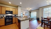 Located at 155 Cross Creek Pkwy in Hattiesburg, MS, this one-bedroom, one-bathroom residence offers a thoughtfully designed open-concept floor plan that maximizes its comfortable footprint. Rich hardwood flooring flows throughout the main living areas, tying together the living room, dining area, and kitchen into a cohesive, inviting space. The living room is anchored by a ceiling fan with light fixture and features large sliding glass doors fitted with vertical blinds, allowing abundant natural light to fill the room. The kitchen is equipped with warm wood cabinetry, granite countertops, a peninsula with a built-in sink, and black appliances, including a full-size refrigerator and microwave. A dedicated dining area adjacent to the kitchen accommodates a full dining set and is brightened by a window with natural light. Crown molding and track lighting add refined architectural detail throughout. The bedroom is a tranquil retreat with plush carpet, a ceiling fan, and a window with outdoor views. It connects to a generously sized walk-in closet with wire shelving and hanging rods on multiple walls. The bathroom features warm wood vanity cabinetry, granite countertops, a large mirror, and a shower/tub combination.