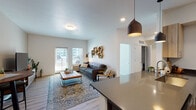 This single-floor unit at 4528 SW 39th St in Redmond, Oregon offers a well-designed, modern interior with a clean, contemporary aesthetic throughout. The open-concept layout connects the kitchen and living area seamlessly, creating a spacious, functional flow. Light wood-style flooring runs throughout the main living spaces, complementing the bright white walls and recessed lighting.

The kitchen is outfitted with light natural wood cabinetry, dark lower cabinets with sleek hardware, stainless steel appliances including a full-size refrigerator and microwave, and a dark countertop that extends into a peninsula — ideal for casual dining or food prep.

The living area is generously proportioned, featuring a large window and glass door that open to a private balcony, allowing abundant natural light to fill the space. A pendant light fixture adds a warm, modern accent near the kitchen transition.

The bedroom features a bold terracotta accent wall, carpet flooring, and a sliding-door closet offering practical storage. The bathroom is finished with light wood vanity cabinetry, white quartz countertops, a large mirror, and wood-look tile flooring, creating a clean, spa-like atmosphere. Overall, the unit presents a cohesive, modern design with warm natural tones.