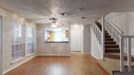 Located in Windcrest, Texas, this two-story home offers a practical and comfortable layout across both levels. The main floor greets you with a spacious open living area finished with warm hardwood-style flooring, a ceiling fan, and a textured ceiling. A pass-through kitchen counter connects the living space to the kitchen, which is equipped with rich wood cabinetry, granite-style countertops, a electric range, and a window that brings in natural light. A bathroom on the main level features a wood-toned vanity with a granite-style countertop and direct access to the kitchen area. The staircase, accented with white balusters and carpeted treads, leads to the upper level. Upstairs, the bedrooms are carpeted for comfort and receive natural light through large windows with blinds. The primary bedroom includes a ceiling fan with vaulted ceiling detail, a walk-in closet, and built-in cabinetry. A full bathroom on the upper level features a wide granite-style vanity, wood cabinetry with mirrored medicine cabinets, and open access to the hallway. Neutral tones and consistent finishes throughout create a cohesive and move-in ready environment.