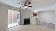 Located at 3003 Windchase Blvd in Houston, TX, this two-bedroom, one-bathroom unit offers a practical and comfortable single-floor layout. The combined kitchen and living room area forms the heart of the home, where a cozy fireplace with a classic white mantle and dark tile surround anchors the living space, complemented by crown molding, a ceiling fan, and plush carpeting. The kitchen features warm wood cabinetry, speckled granite-style countertops, a stainless steel sink, and light wood-look vinyl flooring that extends through the main corridor — a clean, functional galley-style layout with ample storage and a window that brings in natural light.

Both bedrooms are carpeted and equipped with ceiling fans. The primary bedroom is generously sized with a sliding glass door opening to a private balcony, providing outdoor views. The second bedroom includes a window and access to a louvered-door closet. A dedicated walk-in closet with wire shelving offers additional storage. The full bathroom presents a tub-shower combo with tiled surround, a wood-vanity with granite-style countertop, and wood-look flooring, maintaining a cohesive, neutral aesthetic throughout the unit.