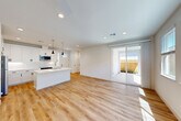 Located at 448 Denton Ave in Vacaville, CA, this thoughtfully designed single-story home offers 2 bedrooms and 2 bathrooms within a well-utilized floor plan. The heart of the home is a bright, open-concept space combining the living room, dining area, and kitchen. Light hardwood flooring flows throughout, complementing the clean white walls and recessed lighting. The kitchen is a standout feature, showcasing a large center island with a quartz countertop and undermount sink, white shaker cabinetry, subway tile backsplash, stainless steel appliances, and sleek black pendant lights. A sliding glass door in the living area connects seamlessly to a covered outdoor patio enclosed by a wood privacy fence with low-maintenance landscaping. The primary bedroom is a comfortable retreat with a ceiling fan, recessed lighting, and a well-sized closet. The bathrooms are finished in a modern style, with one featuring a framed glass walk-in shower and white vanity cabinetry with black hardware accents. Three closets provide ample storage, and a dedicated laundry room and an attached garage add everyday convenience. The home's bright, neutral palette and contemporary finishes create a clean, welcoming atmosphere throughout.