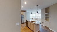 This single-floor residence at 728 N Church St in Spartanburg, SC offers a thoughtfully designed layout with modern finishes throughout. The kitchen is a standout feature, boasting white shaker-style cabinetry reaching to the ceiling, sleek quartz countertops, a classic white subway tile backsplash, and a full suite of stainless steel appliances including a range, microwave, dishwasher, and refrigerator. A center island with a undermount sink and stylish pendant lighting connects the kitchen seamlessly to the dining and living areas, which are bathed in natural light from multiple windows. The living spaces feature warm hardwood-style flooring, while the bedrooms offer plush carpeting and ample natural light through large windows with blinds. Ceiling fans provide additional comfort in the main living area. The bathrooms are elegantly finished with large-format tile surrounds, white vanities with quartz countertops, and wood-style flooring. One bathroom features a walk-in shower, while the other includes a tub-shower combination. A dedicated laundry area accommodates a full-size washer and dryer. The overall ambiance is clean, bright, and contemporary, reflecting a well-executed modern design.