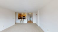 This single-floor residence offers a thoughtfully designed open-concept layout that seamlessly connects the living area to the kitchen. The generously sized living room features plush neutral carpeting, clean white walls, and a large sliding glass door that opens to a private balcony, framing expansive city and skyline views. Natural light fills the space throughout the day, enhancing its bright and airy atmosphere.

The kitchen is well-equipped and functional, showcasing warm honey-toned wood cabinetry, granite countertops, hardwood flooring, and a full suite of stainless steel appliances including a refrigerator, range, microwave, and dishwasher. A raised breakfast bar with seating provides a convenient casual dining option and adds to the open feel of the shared living space.

The bedrooms are carpeted and generously proportioned, each benefiting from large windows that capture sweeping urban views and fill the rooms with natural light. The unit includes two full bathrooms: one featuring a tub-shower combination with sliding glass doors and chrome fixtures, and a second with a soaking tub and a separate shower stall, accompanied by a vanity and tile surround. A hallway connects the living spaces efficiently, completing this well-organized and comfortable residence.
