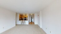 This single-floor residence offers a thoughtfully designed open-concept layout that seamlessly connects the living area to the kitchen. The generously sized living room features plush neutral carpeting, clean white walls, and a large sliding glass door that opens to a private balcony, framing expansive city and skyline views. Natural light fills the space throughout the day, enhancing its bright and airy atmosphere.

The kitchen is well-equipped and functional, showcasing warm honey-toned wood cabinetry, granite countertops, hardwood flooring, and a full suite of stainless steel appliances including a refrigerator, range, microwave, and dishwasher. A raised breakfast bar with seating provides a convenient casual dining option and adds to the open feel of the shared living space.

The bedrooms are carpeted and generously proportioned, each benefiting from large windows that capture sweeping urban views and fill the rooms with natural light. The unit includes two full bathrooms: one featuring a tub-shower combination with sliding glass doors and chrome fixtures, and a second with a soaking tub and a separate shower stall, accompanied by a vanity and tile surround. A hallway connects the living spaces efficiently, completing this well-organized and comfortable residence.