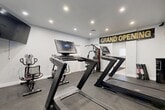 Located in Lauderhill, FL, this fitness and wellness facility offers a well-organized, single-floor layout designed to support both physical training and client services. The two exercise rooms are outfitted with rubber flooring and recessed lighting, housing multiple treadmills with digital displays, a cable machine, and stationary bikes — providing a fully equipped environment for cardio and strength training. A wall-mounted flat-screen TV enhances the workout experience. The office features clean white walls, light tile flooring, and ample natural light from multiple windows with white blinds. It is furnished with dual workstations and a cushioned storage bench, creating a functional and welcoming administrative space. The bathroom showcases modern finishes, including a wood-tone vanity with a marble-style countertop, matte black fixtures, a frameless mirror, and a window that brings in natural light. The unclassified room stands out with a creative, themed design — a space-inspired area featuring a solar system rug, a round table with seating, a wall-mounted TV, and decorative cloud installations overhead, lending a distinctive and imaginative ambiance. Together, these spaces form a comprehensive, client-ready facility.