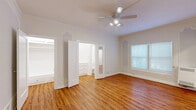 Located at 849 S Gramercy Dr in Los Angeles, this single-floor unit offers a thoughtfully laid-out living space with classic architectural charm. Warm-toned hardwood flooring runs throughout, tying together each room with a cohesive, inviting feel. The living room is a standout feature, showcasing elegant decorative wall moldings, crown molding, and a ceiling fan with integrated lighting. Natural light filters in through multiple windows fitted with blinds, enhancing the bright, airy ambiance. Ornate arched wall niches add a distinctive vintage character to the space. The combined dining and kitchen area is efficiently designed, featuring white cabinetry, granite-look countertops, a gas range, and a refrigerator, with a window that brings in additional natural light. Two hallways provide smooth circulation throughout the unit. The bathroom is clean and classic, with a pedestal sink, a full soaking tub with shower, wood flooring, white tile wainscoting, and a window for ventilation and natural light. The overall aesthetic is bright and neutral, with white walls and trim creating a clean backdrop that highlights the space's architectural detailing. This unit blends vintage character with functional design in a prime Los Angeles location.