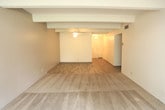 Located at 2201 Ambassador Rd NE in Albuquerque, New Mexico, this single-floor residence offers a well-organized layout with a blend of hard-surface and carpeted flooring throughout. Distinctive exposed beam ceilings lend architectural character to the main living and bedroom areas, creating a warm, structured aesthetic.

The open living area features wood-look plank flooring and a ceiling fan, transitioning seamlessly into the carpeted living space beyond. Large sliding glass doors flood the room with natural light and provide direct access to a private balcony with outdoor views.

The galley-style kitchen is efficiently designed with warm wood cabinetry lining both sides, laminate countertops, a double sink, and white appliances including a coil-top range and refrigerator, all set atop wood-look tile flooring.

The bedrooms are carpeted and generously proportioned, with exposed beam ceilings continuing the architectural theme. The primary bedroom includes louvered closet doors offering ample storage, as well as sliding glass door access to the balcony.

The bathrooms include a full bath with a tub-and-shower combination framed in taupe tile, wood-look flooring, and a vanity with a stone-finish countertop. A second bathroom features a glass-enclosed walk-in shower. Built-in storage is also present in the hallway area, adding practical utility to the space.