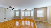 This single-floor residence offers a thoughtfully designed layout that balances comfort and functionality. The spacious living area immediately draws attention with its beautifully polished hardwood floors that reflect natural light streaming in through multiple white-trimmed windows fitted with blinds. A ceiling fan adds both style and practicality to the open, airy space, while neutral taupe walls create a warm and inviting atmosphere throughout.

The kitchen is well-equipped and features rich, dark cherry wood cabinetry that provides generous storage, complemented by granite-look countertops and a full suite of black appliances including a range, over-the-range microwave, and dishwasher. The tile flooring in the kitchen provides a clean contrast to the hardwood found throughout the rest of the home, and a bright window allows for ample natural light in the cooking space.

Additional rooms include well-proportioned bedrooms, each with hardwood flooring and ceiling fans, offering comfortable and versatile living spaces. A dedicated laundry area houses a stacked washer and dryer unit alongside convenient closet shelving.

The bathroom showcases classic design with white subway tile wainscoting, a black accent border, and a traditional black-and-white mosaic tile floor — a timeless aesthetic complemented by a frosted privacy window.