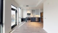 Located at 1250 Half St SE in Washington, DC's vibrant Navy Yard neighborhood, this modern unit showcases a thoughtfully designed open-concept layout with clean lines and contemporary finishes. Light hardwood flooring flows throughout the main living areas, complemented by crisp white walls that enhance the bright, airy atmosphere.

The kitchen is a standout feature, equipped with stainless steel appliances including a gas range, built-in microwave, dishwasher, and refrigerator. Two-tone cabinetry — pairing dark lower cabinets with light upper cabinets — frames a striking hexagonal tile backsplash, while dark stone countertops and a brushed gold undermount sink add refined detail. Floor-to-ceiling windows adjacent to the kitchen flood the space with natural light and offer views of the surrounding cityscape.

The bedroom continues the modern aesthetic with expansive floor-to-ceiling windows that frame urban views and allow generous amounts of natural light to pour in. The bathroom features neutral tile flooring, a full soaking tub with shower, and brushed nickel fixtures for a clean, polished look.

Throughout the unit, large windows and an open layout create a sense of spaciousness, making this a well-appointed residence in one of DC's most dynamic and sought-after neighborhoods.