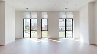 Located in the heart of Indianapolis on N Pennsylvania Street, this modern 2-bedroom, 2-bathroom residence offers a thoughtfully designed open-concept layout with high-end finishes throughout. The expansive living and kitchen area is bathed in natural light through large floor-to-ceiling windows framed in bold black, offering sweeping views of the downtown Indianapolis skyline and surrounding greenery. Light hardwood-style flooring runs throughout the main living areas, enhancing the bright and airy ambiance. The sleek kitchen features a generous island with an undermount sink, crisp white countertops, dark wood cabinetry, stainless steel appliances including a French door refrigerator, and a striking pendant light fixture overhead. A clean, white hallway connects the living spaces to the private quarters, lined with multiple closets for ample storage. Both bedrooms are carpeted for comfort, with the primary bedroom boasting a large window with city views and built-in upper cabinetry. The primary bathroom offers a dual-sink vanity with wood cabinetry and marble-style tile flooring, while the second bathroom features a soaking tub, matching dark fixtures, and wood vanity. A dedicated laundry room and utility space round out this well-appointed urban residence.