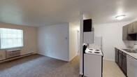 This single-floor residence at 4705 Wilmington Pike in Kettering, Ohio offers a practical and well-organized layout. The open living area features neutral-toned carpet, clean white walls, and a ceiling fan with integrated lighting, creating a comfortable and airy atmosphere. A wall-mounted air conditioning unit and baseboard heating provide year-round climate control, while a window allows natural light to fill the space.

The kitchen is efficiently designed with dark espresso cabinetry lining both sides, light granite-style countertops, and tile flooring. It is equipped with white appliances including a coil-burner electric range, refrigerator, dishwasher, and an over-the-range microwave, offering full functionality in a compact galley-style configuration.

The living and kitchen areas connect seamlessly, with the transition from tile to carpet clearly delineating each zone. The bedroom is generously sized, with soft carpet underfoot, a ceiling fan, a window with blinds providing natural light, and baseboard heating for added comfort.

The bathroom is clean and straightforward, featuring a full-size tub and shower combo with white surround panels, brushed nickel fixtures, and a toilet. Throughout the unit, the design emphasizes clean lines and a neutral palette, making it easy to personalize.