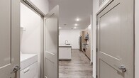 This single-floor unit offers three bedrooms, two bathrooms, and a well-designed open-concept layout that maximizes functionality. The kitchen serves as a central highlight, featuring light wood cabinetry with black hardware, a white subway tile backsplash, stainless steel appliances including a refrigerator, electric range, and microwave, and a center island with a gray quartz countertop and integrated sink. Wood-look luxury vinyl plank flooring runs throughout the main living areas, complementing the clean, neutral color palette.

The living room benefits from natural light through windows fitted with blinds and includes a ceiling fan, with a door providing direct exterior access. Bedrooms are carpeted for comfort, with at least one featuring a window and a double-door closet with rod and shelf storage. Two dedicated closets serve the unit for additional storage needs.

The primary bathroom includes a glass-enclosed walk-in shower, a dual-sink vanity with quartz countertops, light wood cabinetry, and wood-look flooring. The secondary bathroom offers a full tub-shower combo with white tile surround, a single-sink vanity, and matching cabinetry. Recessed lighting throughout the unit creates a bright, modern ambiance.