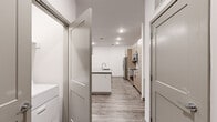 This single-floor unit offers three bedrooms, two bathrooms, and a well-designed open-concept layout that maximizes functionality. The kitchen serves as a central highlight, featuring light wood cabinetry with black hardware, a white subway tile backsplash, stainless steel appliances including a refrigerator, electric range, and microwave, and a center island with a gray quartz countertop and integrated sink. Wood-look luxury vinyl plank flooring runs throughout the main living areas, complementing the clean, neutral color palette.

The living room benefits from natural light through windows fitted with blinds and includes a ceiling fan, with a door providing direct exterior access. Bedrooms are carpeted for comfort, with at least one featuring a window and a double-door closet with rod and shelf storage. Two dedicated closets serve the unit for additional storage needs.

The primary bathroom includes a glass-enclosed walk-in shower, a dual-sink vanity with quartz countertops, light wood cabinetry, and wood-look flooring. The secondary bathroom offers a full tub-shower combo with white tile surround, a single-sink vanity, and matching cabinetry. Recessed lighting throughout the unit creates a bright, modern ambiance.